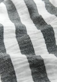 Țesătură cu dungi alternative groase, negre și albe, realizată dintr-un material ușor, cu o suprafață moale, ușor texturată.