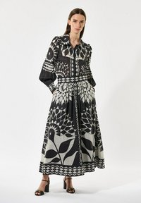 Black and white patterned dress with long puff sleeves, collared neck, cinched waist, and pockets. Features floral and geometric designs.