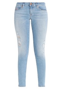 Jeans skinny de mezclilla azul claro con una cintura alta, que presentan dos desgastes en las rodillas, diseño clásico de cinco bolsillos y botones de cobre.