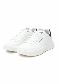 Zapatillas blancas de cuero con punta redondeada, cierre de cordones en la parte delantera, acentos en el talón en negro y detalles de costura. Presentan la marca "Teddy Smith" en el lado.