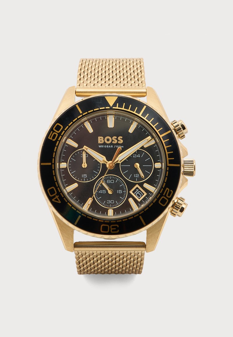 Χρυσόχρωμο ρολόι χειρός Hugo Boss με μαύρο καντράν, τρεις υποκαντράν, παράθυρο ημερομηνίας στη θέση 4 και μπρασελέ από δίχτυ.