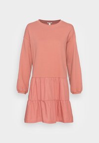 Vaaleanpunainen pitkähihainen mekko, joka on valmistettu pehmeästä puuvillasta ja jossa on pyöreä kaula-aukko. Mekossa on kerroksellinen röyhelöhame ja kuminauhakäytävät.