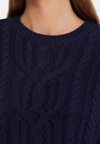 Námořnický modrý pletený svetr s texturovaným vzorem kabelu, kulatým výstřihem a žebrovanými manžetami. Pletený z objemné, měkké příze.