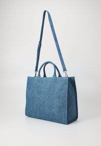 Jeansväska i blått, med rektangulär form, dubbla handtag upptill och ett justerbart axelband. Enkel, texturerad tyg.