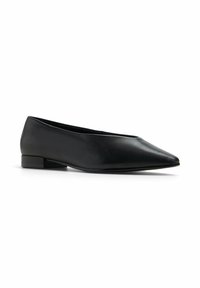 Scarpe flat nere in pelle con punta affusolata e tacco basso. Texture liscia con un profilo minimalista, senza hardware visibile.