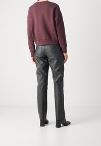 Sweat-shirt bordeaux à épaules tombantes associé à un pantalon droit en cuir noir, présentant une texture lisse et un design minimaliste.