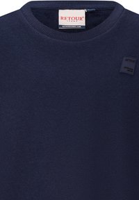 Maglione crewneck navy realizzato in tessuto morbido, con scollatura a costine e una piccola etichetta con logo sul petto. Texture liscia e design semplice.