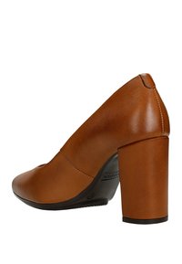 Chaussure à talons hauts en cuir marron avec un bout arrondi et un talon épais. Présente une texture lisse et des détails de couture minimaux.