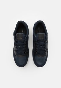 Sneaker navy con tomaia in pelle liscia e rete, design con lacci, colletto imbottito e suola in gomma testurizzata. Presenta un logo sulla linguetta.
