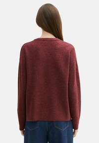 Burgundský vlněný svetr s uvolněným střihem, ribbovaným lemem a kulatým výstřihem. Textura vypadá měkce s mírně melírovaným efektem.