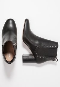 Černé kotníkové boty z hladké kůže s kulatou špičkou, elastickými bočními panely, stříbrnými cvočky a blokovým podpatkem.