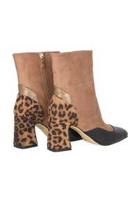 Botas de tobillo de ante marrón con punta de cuero negro, tacones de bloque con estampado de leopardo y un detalle de cremallera dorada en la parte posterior.