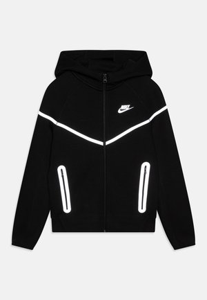 Schwarzer Nike Kapuzenpullover mit Reißverschluss, reflektierendem weißen Chevron auf der Brust und reflektierenden Reißverschlüssen an den vorderen Taschen, mit Kapuze.