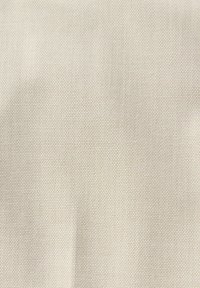 Tejido de color beige claro con un patrón texturizado y tejido, que muestra una sutil variación en el tono y una superficie suave.