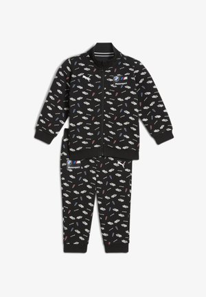 Czarny dres z zamkiem błyskawicznym, składający się z kurtki i spodni. Materiał pokryty jest małymi białymi samochodami oraz błyskawicami w niebieskim i czerwonym kolorze.