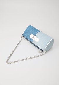 Denim pouch with light and dark blue sections, zip closure, white label, and silver chain strap, featuring a cylindrical shape and smooth texture.