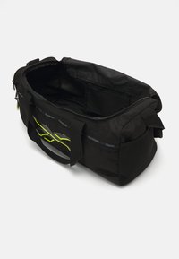 Black sports duffle bag with green accents, featuring a zip closure, two handles, and a mesh side panel for ventilation.