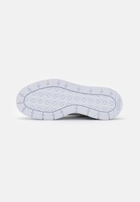Suola di scarpa con una superficie in gomma bianca strutturata che presenta un motivo geometrico e lugs di trazione prominenti. Branding sottile sul bordo.