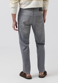 Grijze denim jeans met een rechte pijp, voorzien van twee achterzakken en subtiele stiksels. Draagt met casual sandalen.