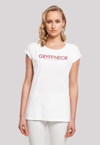 Hvid bomulds T-shirt med opviklede ærmer, der har et Gryffindor-logo i rød og guld på brystet, med rene linjer og en afslappet pasform.