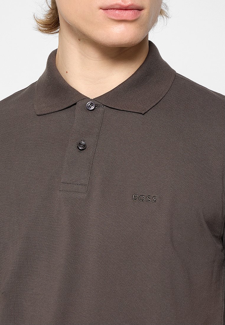 Polo shirt marron foncé avec un tissu texturé, patte de boutonnage à deux boutons et logo "BOSS" brodé sur la poitrine gauche. Design de col classique.