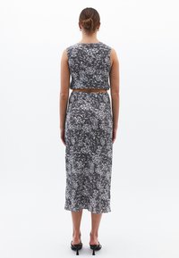 Vestido de dos piezas con estampado floral en blanco y negro, con un top corto ajustado y una falda larga, hecho de telas ligeras.