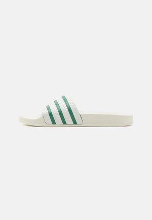 Biała klapka Adidas z trzema zielonymi paskami na pasku i tłoczonym logo Adidas na boku podeszwy.