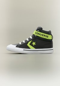Μαύρο ψηλό παπούτσι Converse με λευκή σόλα και κορδόνια, νεον πράσινο αστέρι και ζιγκ-ζαγκ, και λουράκι σε νεον πράσινο χρώμα με την ένδειξη "CONVERSE".