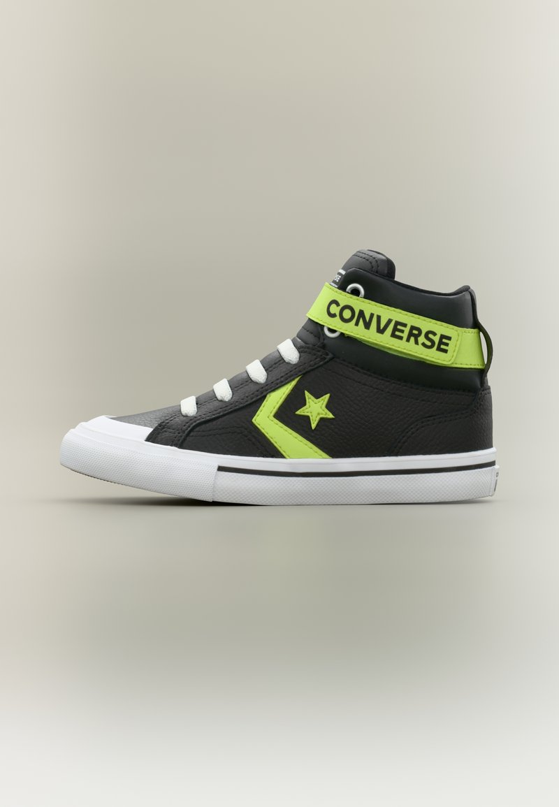 Μαύρο ψηλό παπούτσι Converse με λευκή σόλα και κορδόνια, νεον πράσινο αστέρι και ζιγκ-ζαγκ, και λουράκι σε νεον πράσινο χρώμα με την ένδειξη "CONVERSE".