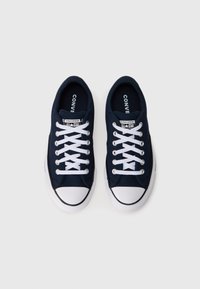 Navy blue canvas sneakers with white laces and rubber toe caps, featuring a textured sole and branded tongue label.