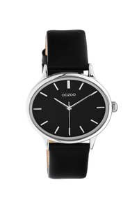 Montre avec bracelet en cuir noir, cadran noir rond, index argentés et boîtier en acier poli. Dispose d'une aiguille centrale pour le réglage de l'heure.