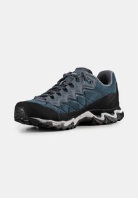 Buty sportowe z ciemnoniebieskiego zamszowego wierzchu, czarnym gumowym noskiem, teksturowaną podeszwą środkową i wzorzystą podeszwą zewnętrzną. Posiadają szare siateczkowe wyściółki i sznurówki.