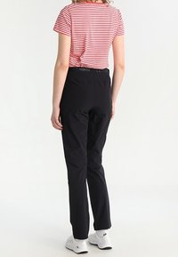 Black, lightweight pants with an elastic waistband, paired with a red-and-white striped short-sleeve top. The shoes are white sneakers.