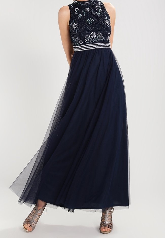 Navy maxi dress with a beaded, sleeveless bodice; sheer tulle skirt; silver accents at the waist. Paired with metallic strappy heels.