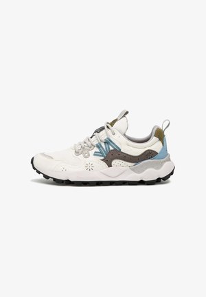 Zapatilla blanca con acentos en gris, azul y oliva. Presenta un acabado texturizado, suela gruesa y perforaciones decorativas. Diseño con cordones y etiqueta en el talón.