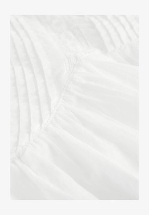 Witte stof met plooien en een zachte, doorschijnende textuur. Het materiaal vertoont een licht, vloeiend ontwerp, met plooien aan de onderkant.