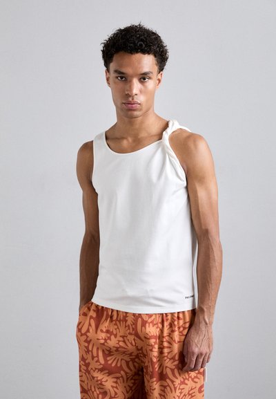 White sleeveless tank top with a twisted shoulder detail, paired with orange patterned shorts featuring a coral-like design.