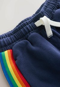 Mørkeblå svedshorts med elastisk talje og hvid snor. Har et regnbuefarvet bånd på siden i rød, orange, gul, grøn og blå.