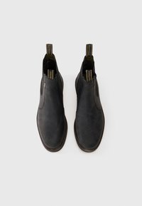 Bocanci din piele neagră până la glezne, cu o textură netedă, panouri laterale elastice și un tab de prindere. Design minimalist, vârful rotund și talpă maro.