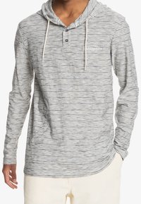 Grå och vit randig långärmad hoodie med knappslå och framficka, tillverkad av mjukt tyg. Försedd med dragsko vid huvan.