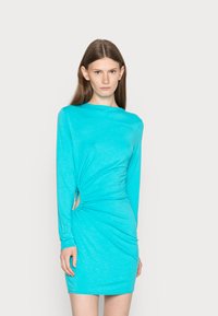 Vestido azul-turquesa de mangas longas feito de tecido macio, apresentando um lado drapeado com um detalhe recortado e uma silhueta ajustada ao corpo.