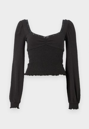 Must have pikad varrukad must T-särk ruudukujulise dekolteega, millel on volditud tekstuur ja pitsi aktsendid. Volangidega äär ja mansetid annavad sobiva disaini.