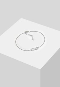 Pulsera de plata con un símbolo de infinito en el centro, cuenta con una delicada cadena y un cierre ajustable para un ajuste personalizado.
