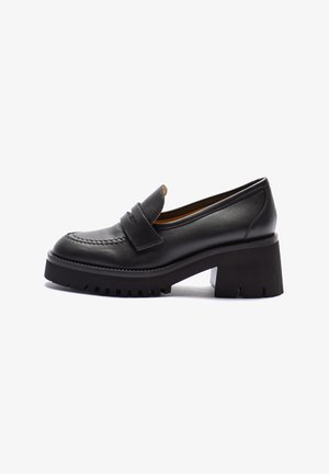 Black leather loafers with a chunky, textured sole and raised heel. Features a stitched toe cap and a decorative strap across the instep.