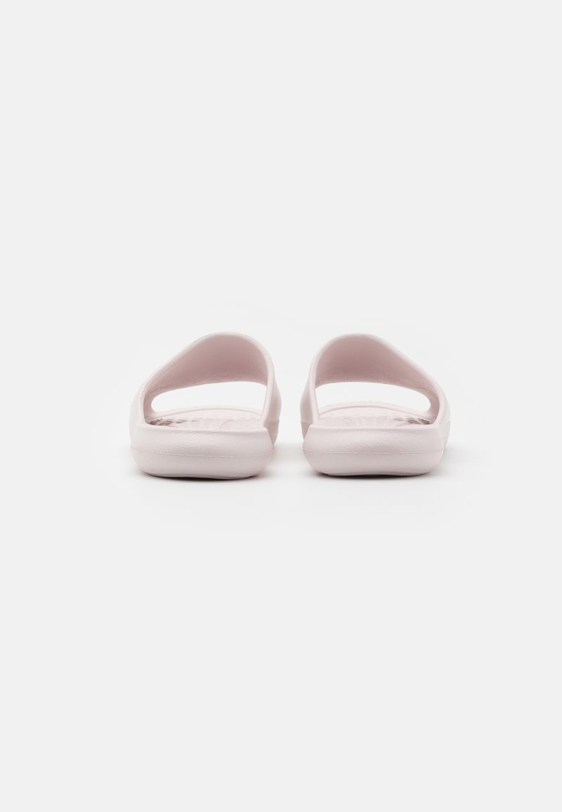 Sandales en caoutchouc roses avec un design ouvert à l'arrière, présentant une texture lisse et des bretelles larges. La semelle est plate et légèrement plus épaisse au niveau du talon.