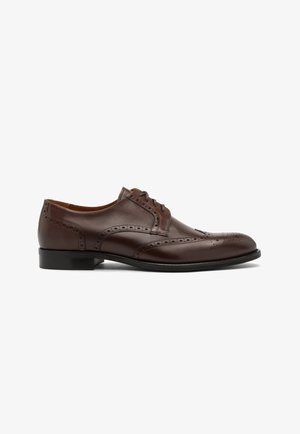 Pruunist nahast kleitking, millel on ümar varvas, paelad, brogue detailid ja madal, lame must talla. Ühtlane sile tekstuur.