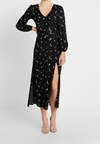 Sort blomster midi kjole med lange ærmer, v-udskæring, frontknapper, sideslids og blødt, let stof med små lyserøde rosemønstre.
