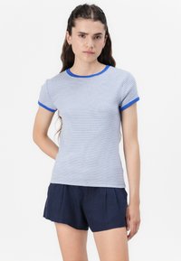 Ραβδωτό μπλε και λευκό T-shirt με στρογγυλή λαιμόκοψη και κοντά μανίκια, με μπλε περιθώριο στην λαιμόκοψη και τα μανίκια. Συνδυάζεται με ναυτικά σορτς.