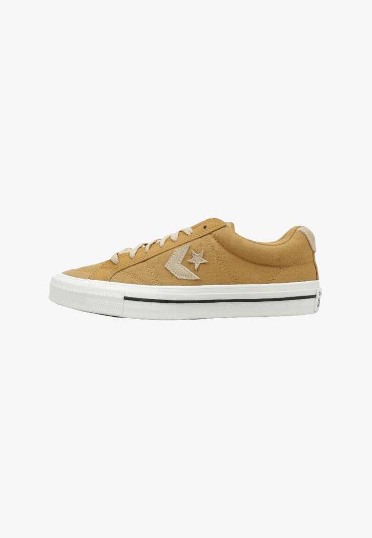 Baskets basses en toile beige avec lacets beiges, semelle en caoutchouc blanc avec bande noire, et logo étoile sur le côté.