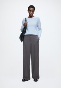 Hele sinise triibuline kampsun, hallid laia säärega püksid, mustad jalanõud ja must õlakott. Siidine tekstuur, vabaaja stiil ja kaasaegne lõige.